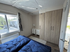 Ein Schlafzimmer mit Bett, Kommode, Kleiderschrank und Fenster.