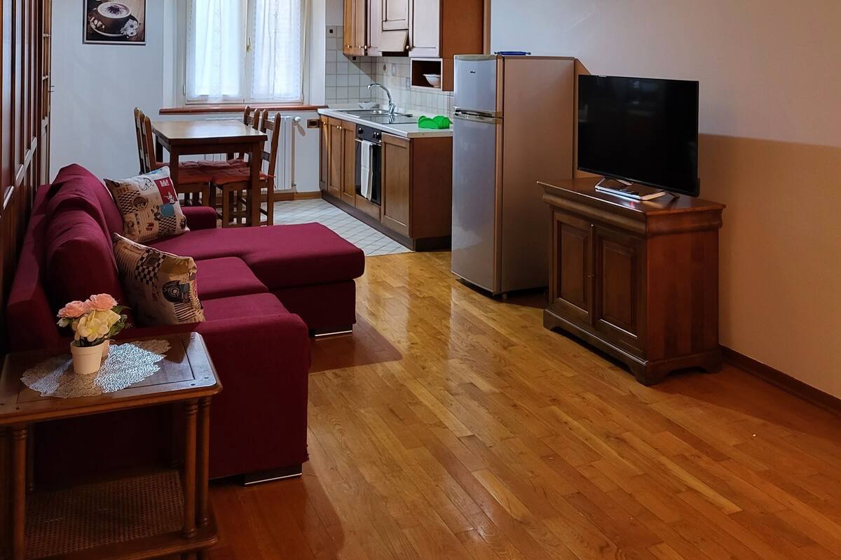 A cozy living room with a sofa, a TV, and a wooden ceiling.
