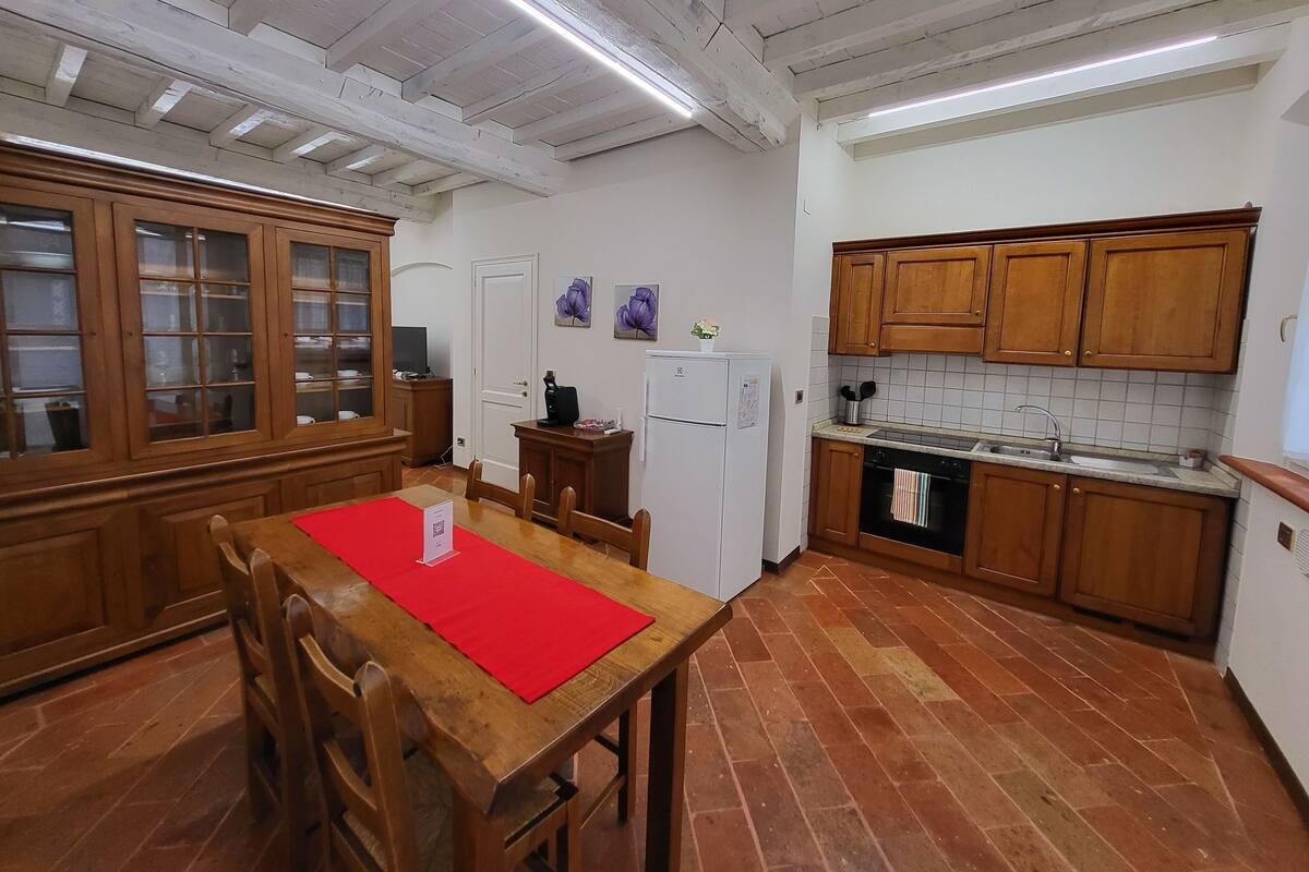 A kitchen with wooden cabinets, a tiled backsplash, a white refrigerator, and a dining area with a red placemat.