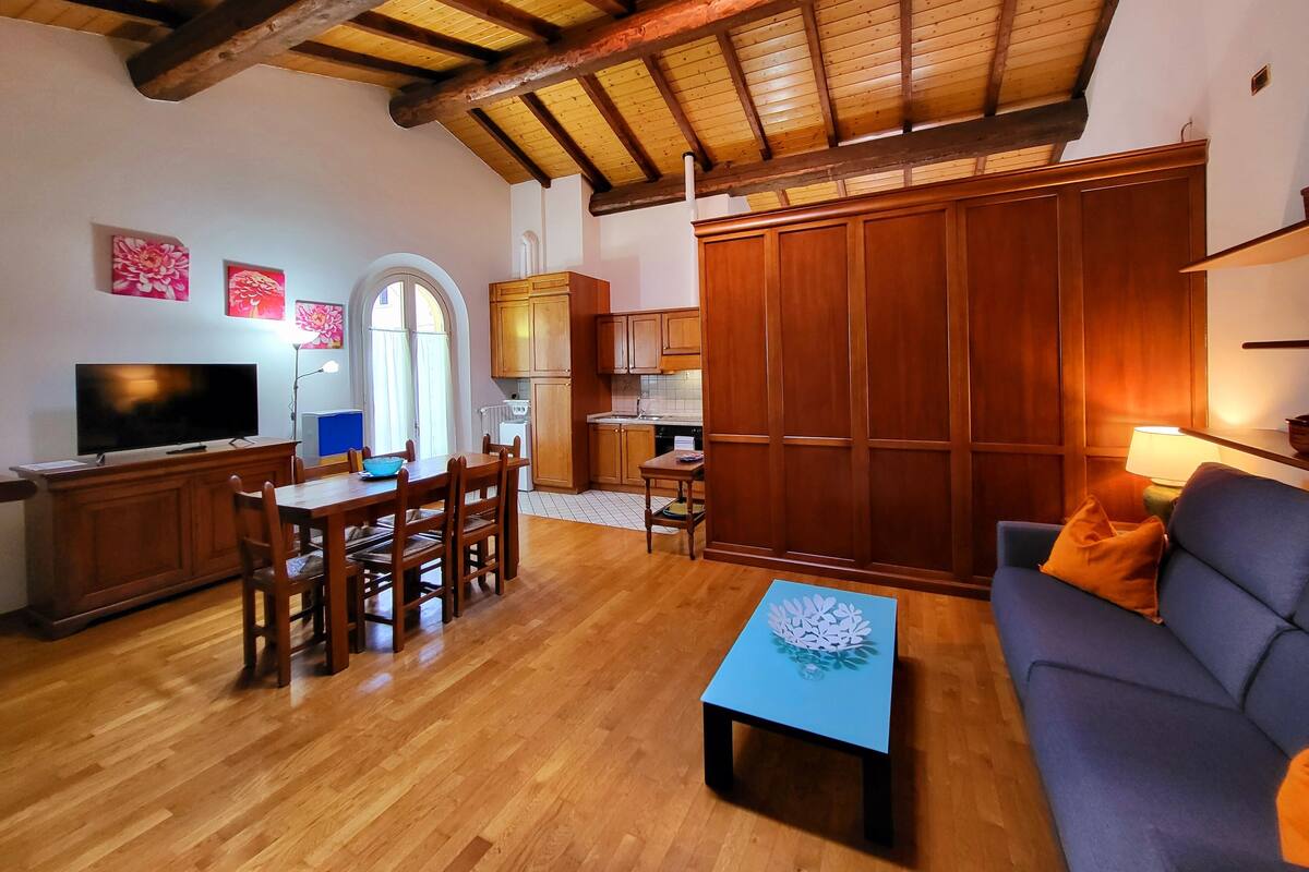 A cozy living room with a wooden dining table, a sofa, and a TV.