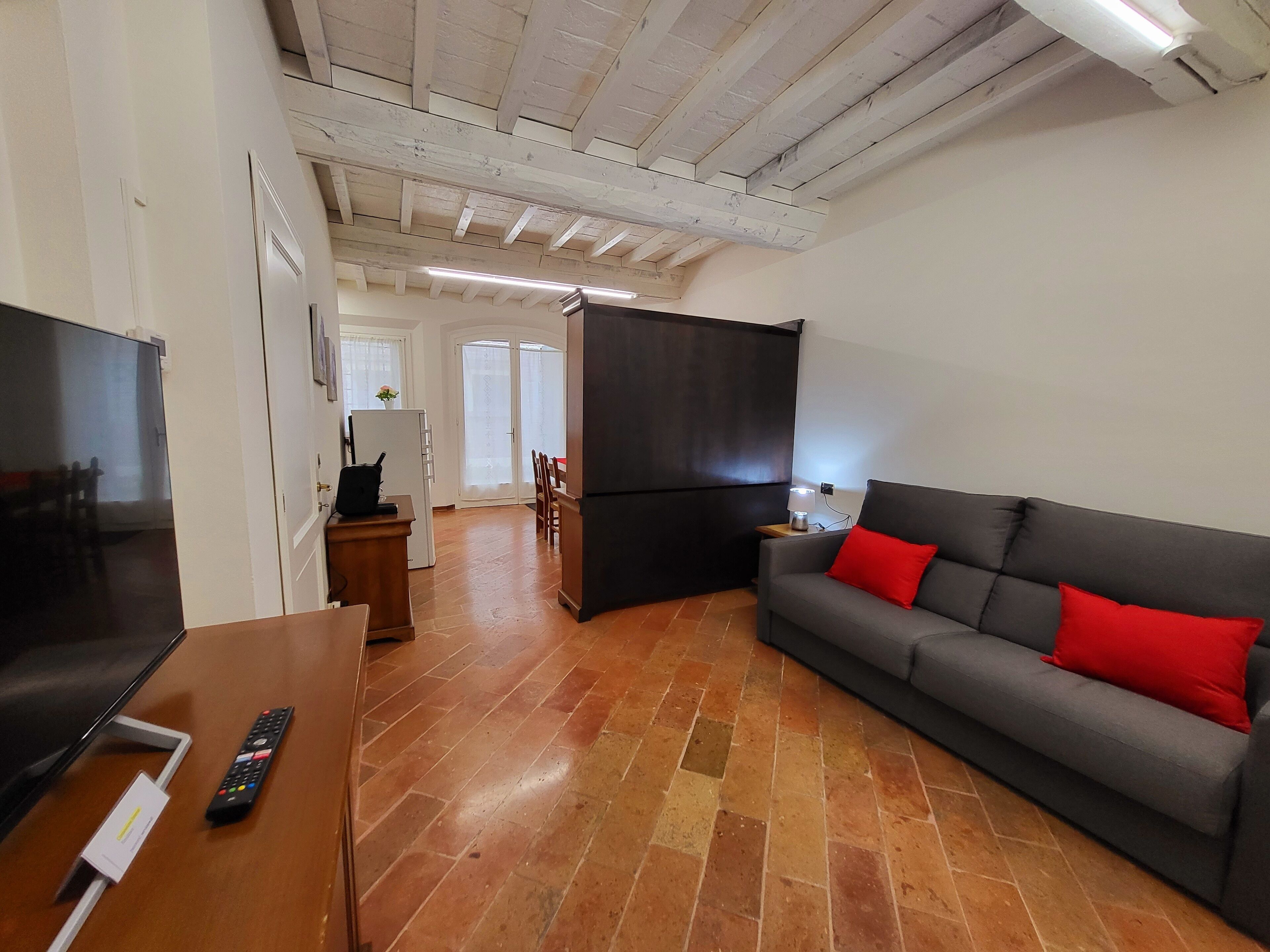 A living room with a TV, sofa, and a dining area with chairs and a table.