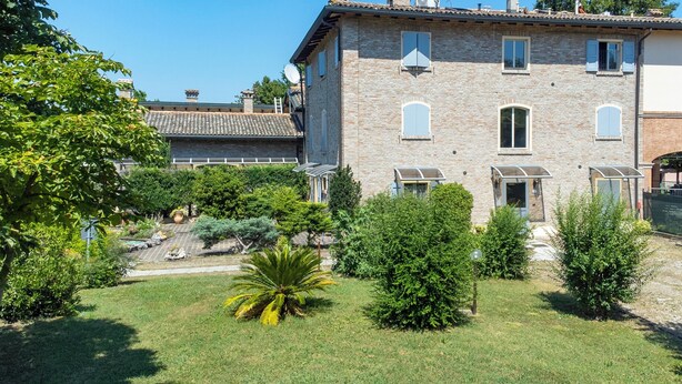 A two-story stone building with a garden in front. - Residence Antico Borgo (Modena)