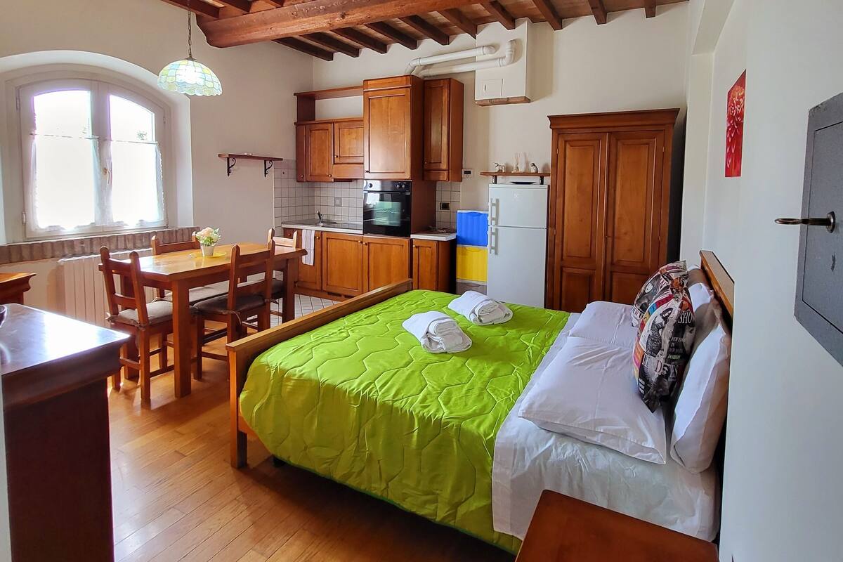 A compact room with a bed, a dining table, and a kitchenette.