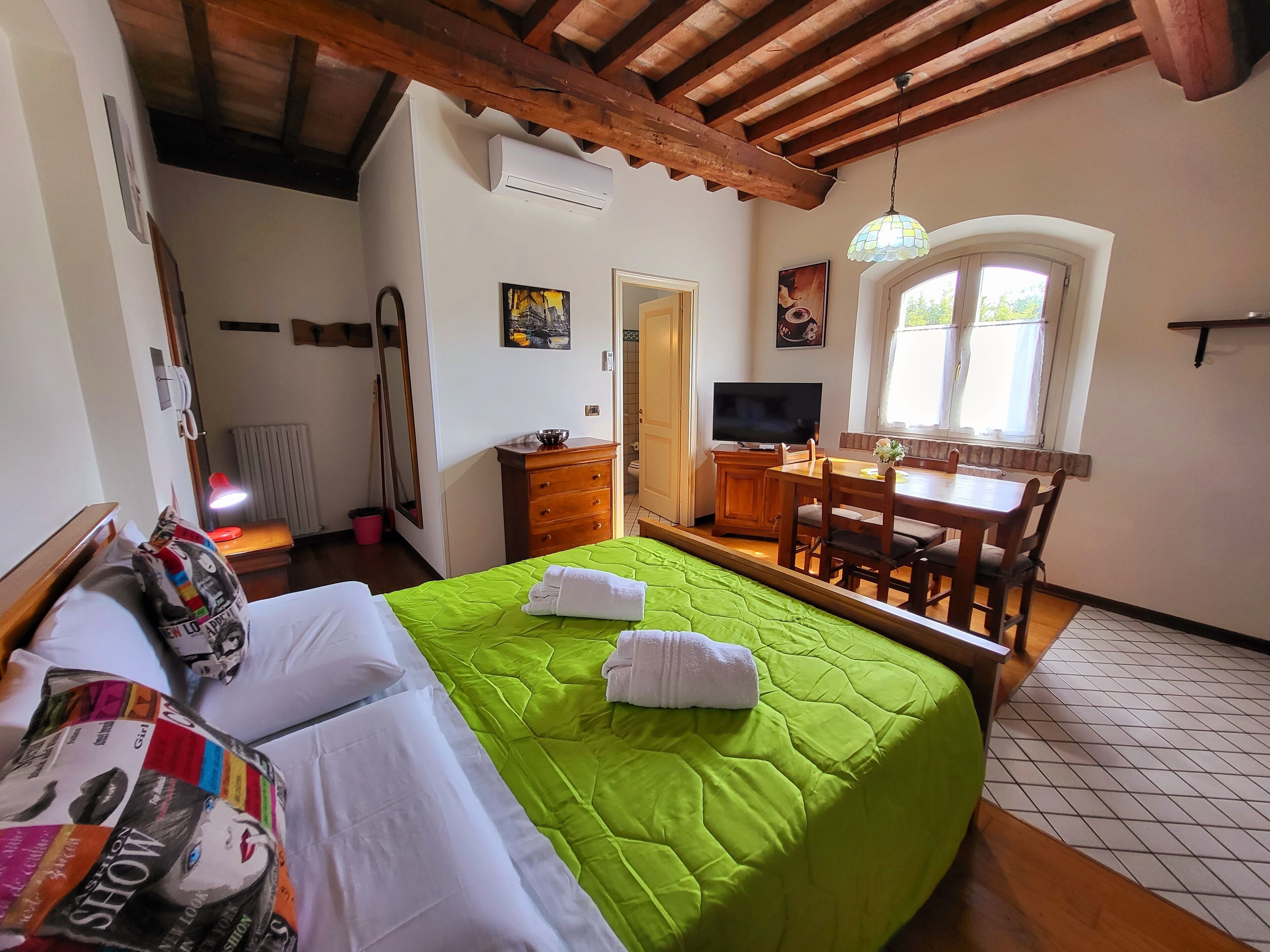 A hotel room with a bed, a desk, a chair, a television, and a window.