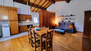A spacious kitchen with wooden cabinets and a dining area with a table and chairs. - Residence Antico Borgo (Modena)
