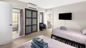 Camera d'albergo con due letti, televisione, una sedia e vista sull'esterno.
