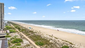 Una spiaggia con un grattacielo sullo sfondo, sabbia dorata e cielo sereno.