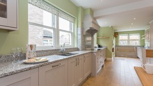 Una cocina moderna con encimeras de granito, armarios blancos y un ventanal que proporciona luz natural.