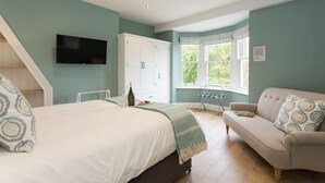 Un dormitorio con cama, sofá, televisión, ventana y armario.