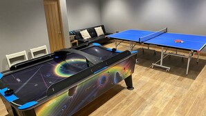 A pool table with a colorful design, a ping pong table, and a sofa in a room with wooden flooring and grey walls. - Unsliven Bridge Farm - sleeps 15 guests  in 7 bedrooms (Stocksbridge)