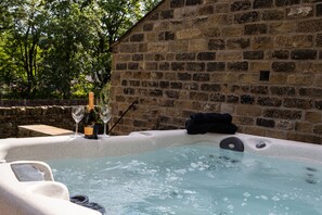 Un muro de piedra, una bañera de hidromasaje y una botella de champán.