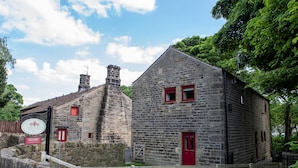 A stone building with red doors and windows, a sign indicating Yorkshire, and a wooden fence. - Unsliven Bridge Farm - sleeps 15 guests  in 7 bedrooms (Stocksbridge)