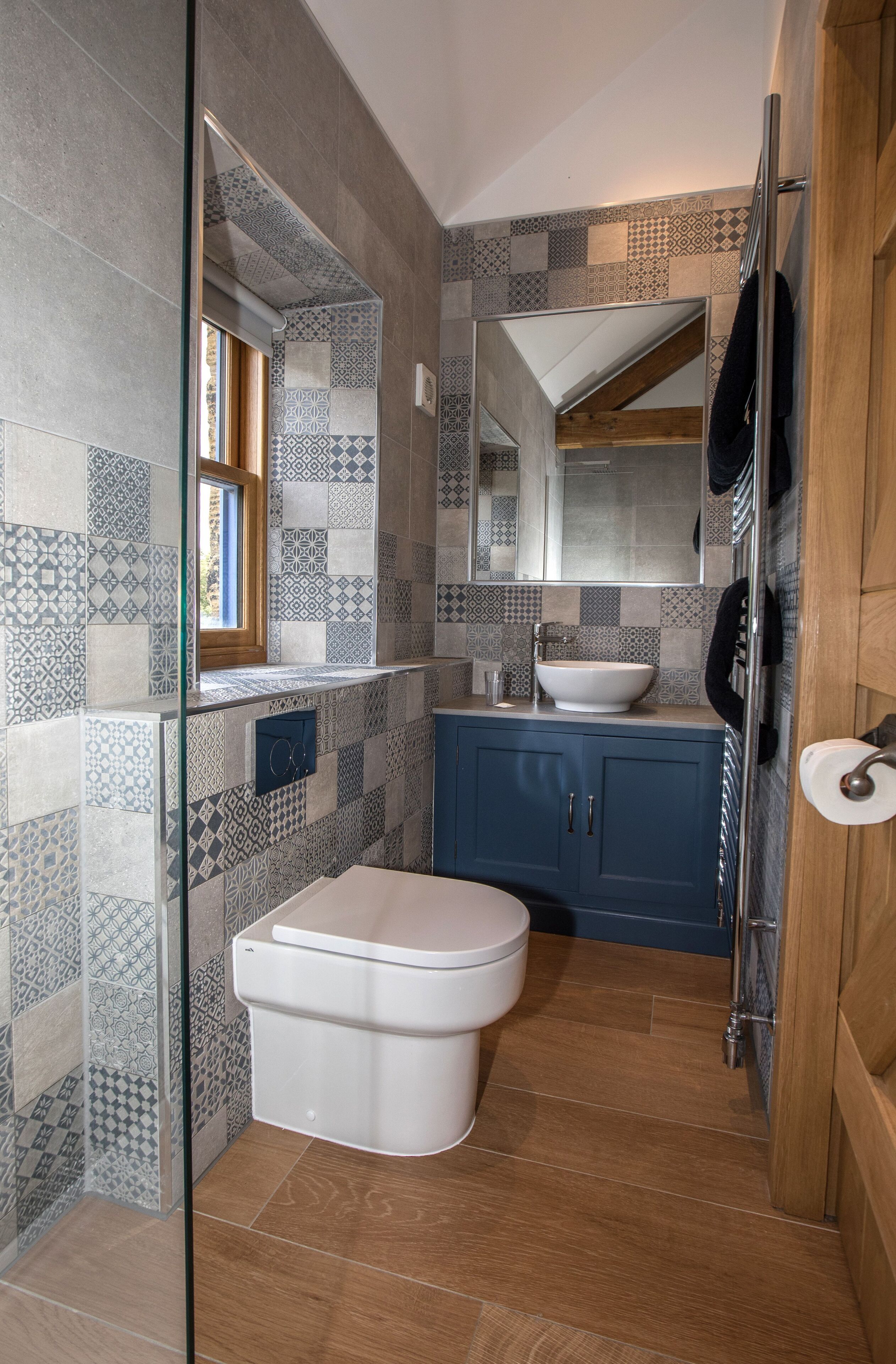 A modern bathroom with a white toilet, a sink with a vessel basin, and a blue cabinet.