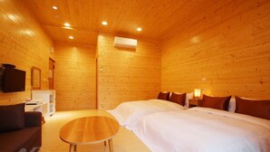 Una habitación de madera con dos camas, un sofá, una mesita y un televisor.