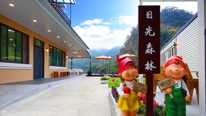 Un edificio moderno con un espacio de estar al aire libre cubierto, un letrero con caracteres japoneses y dos figuritas decorativas.