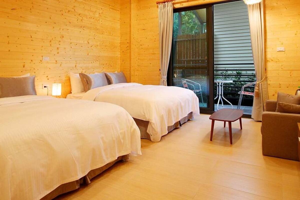 A wooden cabin with two beds, a small table, and a sofa.
