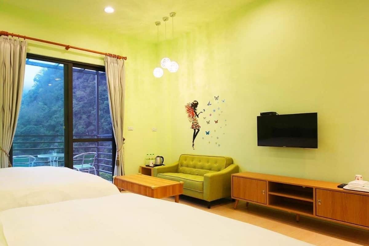A room with a bed, a green sofa, a TV, and a window with curtains.