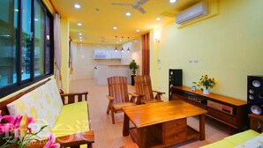Una sala de estar moderna con muebles de madera, una mesa de comedor y una cocina al fondo.