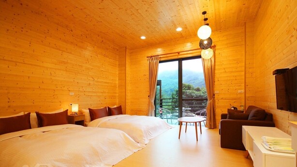 Una habitación de cabaña de madera con dos camas, un sofá, una mesa y un televisor.