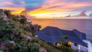 A coastal property with a house overlooking the sea, surrounded by greenery and rocks. - Maxi Cooper Bay (Road Town)