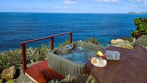 A hot tub with a view of the ocean, a wooden deck, and a towel and flower arrangement. - MyALL Tortola (Road Town)