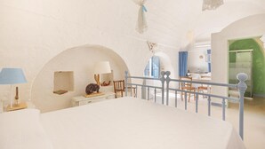 Un dormitorio con cama, un escritorio y una silla. Hay una ventana con cortinas azules.