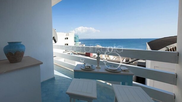 A balcony with a view of the sea, a vase, and a table with plates and glasses. - Attico Barca by BarbarHouse (Gallipoli)