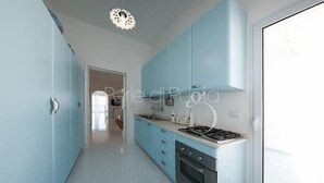 A modern kitchen with light blue cabinets, a gas stove, and a white countertop. - Attico Barca by BarbarHouse (Gallipoli)