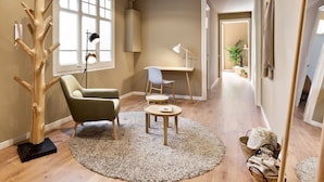 A modern living room with a wooden tree sculpture, a green armchair, a round coffee table, and a desk with a chair. - Ola Living Diagonal B 4-2 (Barcelona)