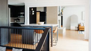 A modern kitchen with dark cabinets, a microwave, and a dining area with a white table and chairs.
