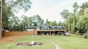 A large house with a deck, a swimming pool, and a stone fire pit.