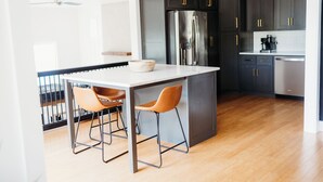 A modern kitchen with dark cabinets, stainless steel appliances, and a marble countertop.