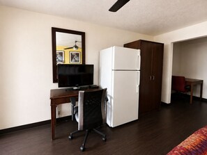 A hotel room with a desk, chair, refrigerator, wardrobe, and a bed. - Vernals Best Value Inn (Vernal)