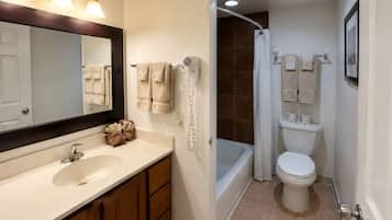 A bathroom with a sink, mirror, towel rack, shower, and toilet.