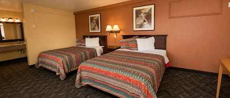 A hotel room with two beds, a bathroom, and a small table.