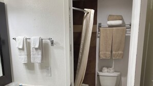 Un baño con lavamanos blanco, armarios de madera, cortina de ducha y un inodoro.