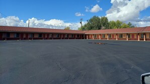 Un motel con varias habitaciones, un estacionamiento y cielo despejado con nubes.