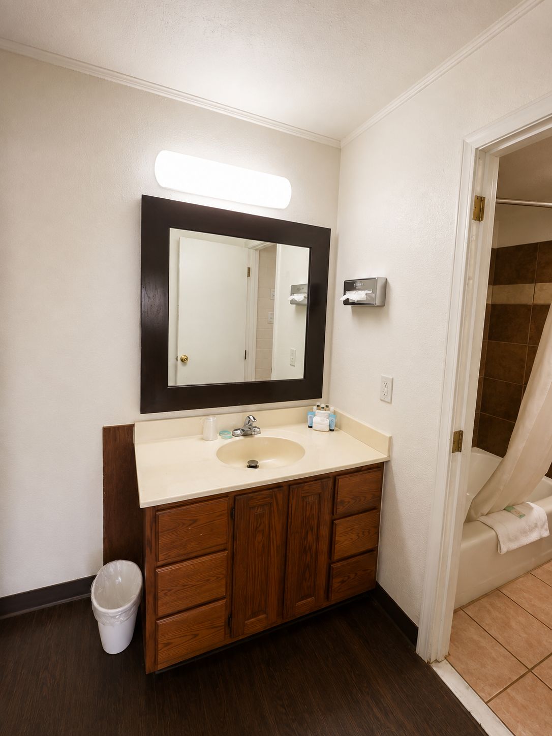 Un baño con tocador de madera, un lavabo, un espejo y zona de ducha.