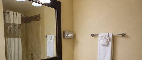 A bathroom with a sink, mirror, towel rack, toilet, and shower curtain.