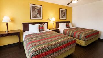 Habitación de hotel con dos camas, ventilador de techo y obras de arte en las paredes.