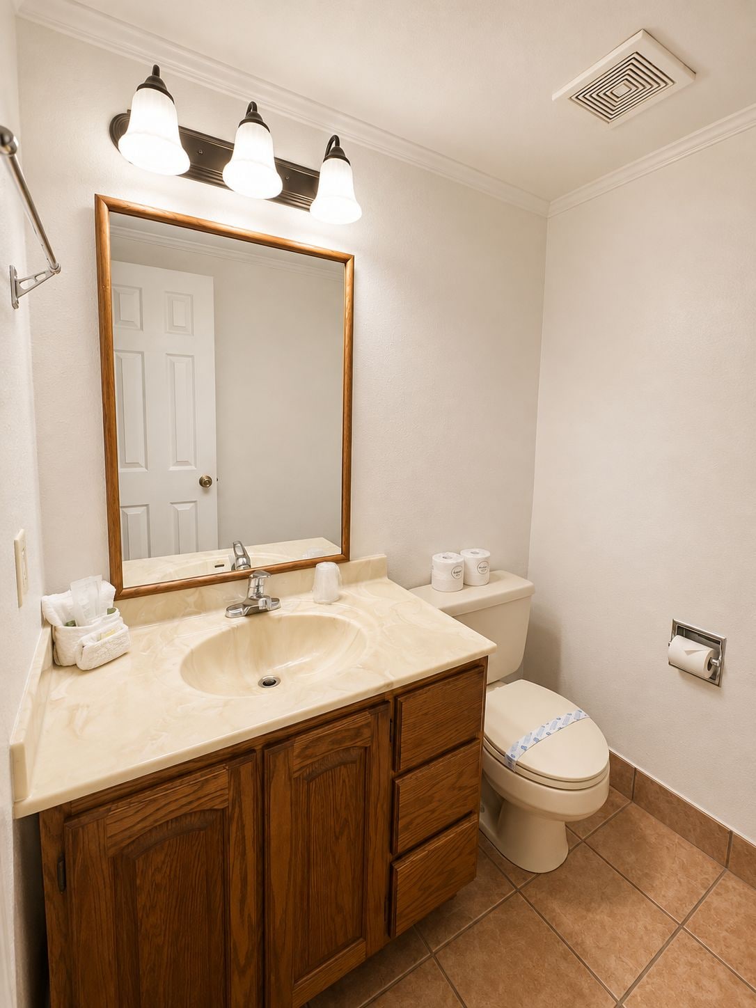 A bathroom with a sink, mirror, toilet, and towel rack.