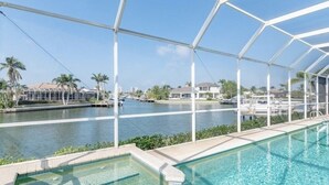 A pool area with a clear view of a marina and houses in the background. - Stunning Sunsets, Spacious Waterfront Home (Marco Island)