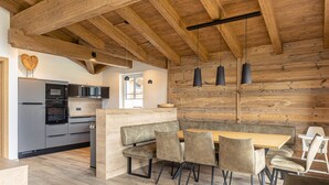 A modern kitchen with wooden beams, a central island, and built-in appliances. - Superior chalet # 2B with sauna (Uttendorf)