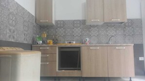 A kitchen with wooden cabinets, a built-in oven, and a tiled backsplash. - Bright apartment with garden (الكورة)