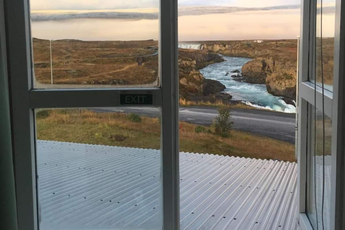 A view from a window with an 'EXIT' sign, overlooking a coastal landscape with a road and cliffs.
