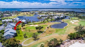 An aerial view of a golf resort with multiple buildings, water bodies, and well-maintained green spaces. - Minute walk to the Beach! Florida Condo with screened in porch. (Stuart)