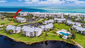 An aerial view of a resort with multiple buildings, a swimming pool, and a body of water. - Minute walk to the Beach! Florida Condo with screened in porch. (Stuart)