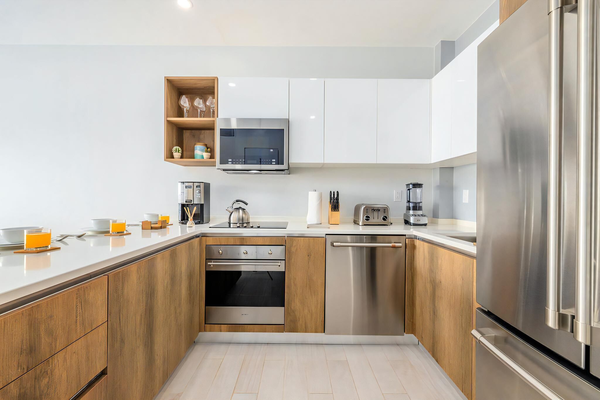 A modern kitchen with wooden cabinets, stainless steel appliances, a built-in oven, and a dishwasher.