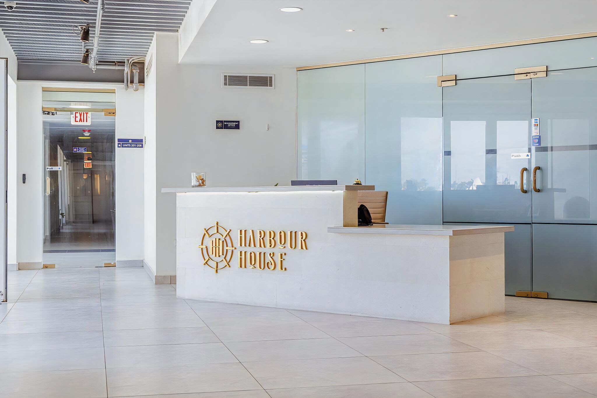 Un mostrador de recepción con un cartel que dice "Harbour House" y una puerta de cristal con un tirador.