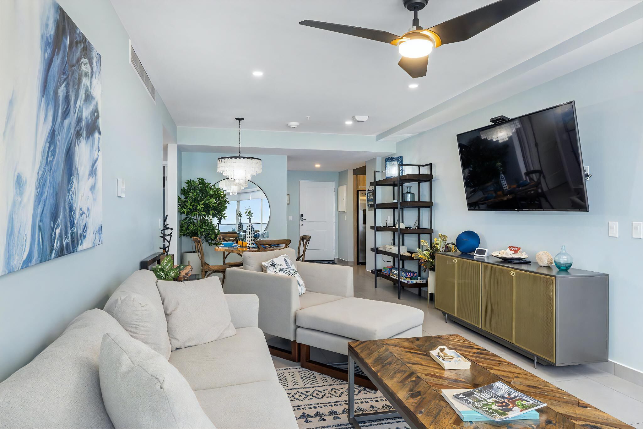 A modern living room with a sofa, coffee table, and a TV mounted on the wall.